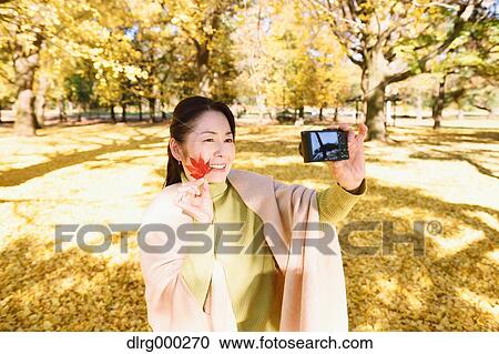 Senior Japanese woman taking a selfie in a city park in Autumn View Large Photo Image Stock Image - Senior Japanese woman taking a selfie in a city park in Autumn. Fotosearch