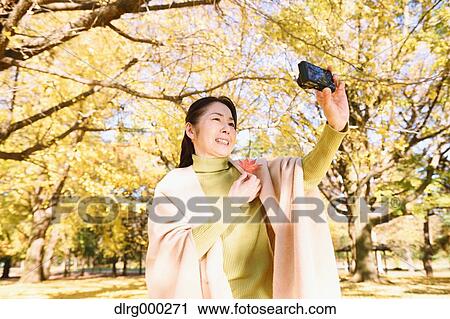 Senior Japanese woman taking a selfie in a city park in Autumn View Large Photo Image Stock Image - Senior Japanese woman taking a selfie in a city park in Autumn. Fotosearch