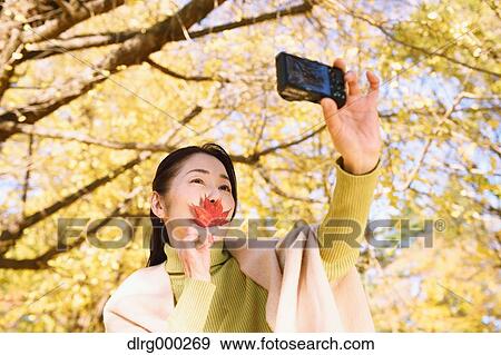Senior Japanese woman taking a selfie in a city park in Autumn View Large Photo Image Stock Photo - Senior Japanese woman taking a selfie in a city park in Autumn. Fotosearch