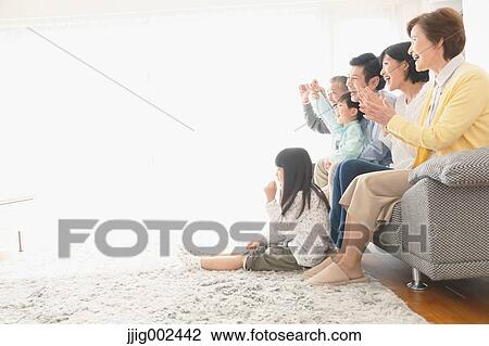 Stock Image - Three-generation Japanese family on the sofa in the living room. Fotosearch