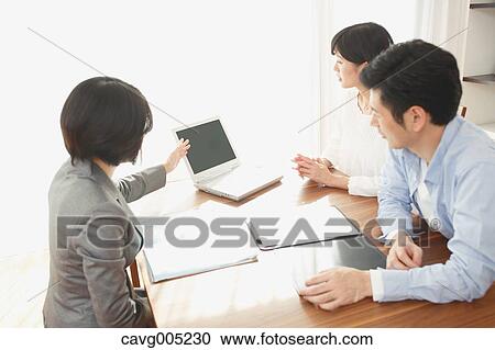 Stock Image - Young Japanese couple consulting with financial planner. Fotosearch