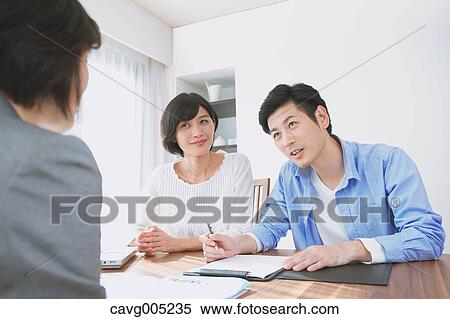 Stock Photography - Young Japanese couple consulting with financial planner. Fotosearch