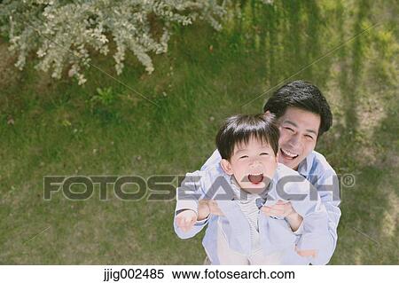 Stock Photography - Young Japanese man playing with his son. Fotosearch