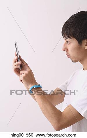 Stock Image - Young Japanese man using smartphone. Fotosearch