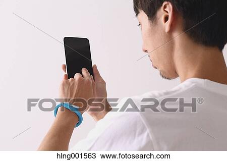 Stock Image - Young Japanese man using smartphone. Fotosearch