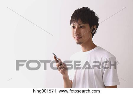 Young Japanese man using smartphone with wireless earphone View Large Photo Image Stock Image - Young Japanese man using smartphone with wireless earphone. Fotosearch