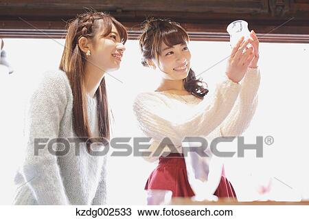 Stock Image - Young Japanese women enjoying visit to glass workshop in Kawagoe, Japan. Fotosearch