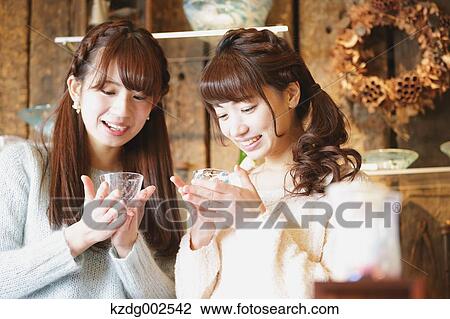 Stock Image - Young Japanese women enjoying visit to glass workshop in Kawagoe, Japan. Fotosearch