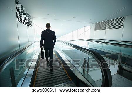 Stock Image - Caucasian businessman on escalator. Fotosearch