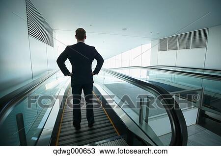 Stock Image - Caucasian businessman on escalator. Fotosearch