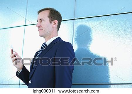 Stock Image - Caucasian businessman with phone in modern office. Fotosearch