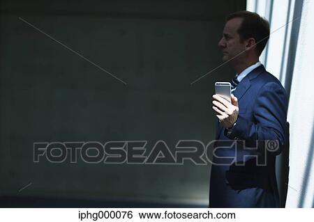 Caucasian businessman with phone in modern office View Large Photo Image Stock Photograph - Caucasian businessman with phone in modern office. Fotosearch
