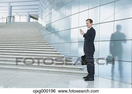 Caucasian businessman with phone in modern office View Large Photo Image Stock Photograph - Caucasian businessman with phone in modern office. Fotosearch