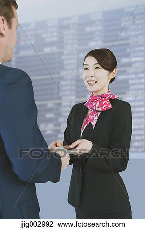 Stock Image - Japanese attractive flight attendant helping customer at the airport. Fotosearch