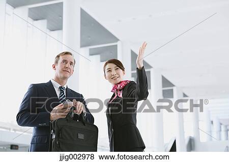 Stock Photo - Japanese attractive flight attendant helping customer at the airport. Fotosearch