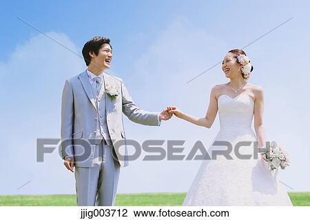 Stock Image - Japanese bride and groom in a city park. Fotosearch