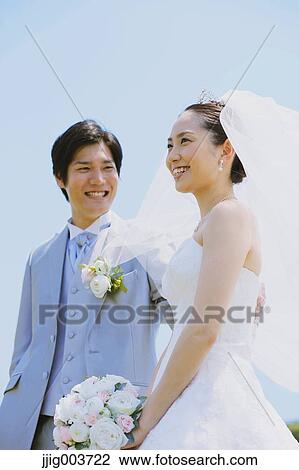 Stock Image - Japanese bride and groom in a city park. Fotosearch
