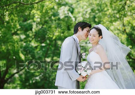 Stock Image - Japanese bride and groom in a city park. Fotosearch