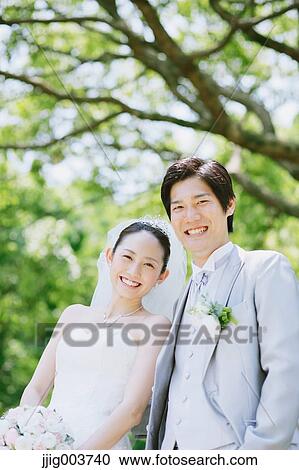 Stock Image - Japanese bride and groom in a city park. Fotosearch