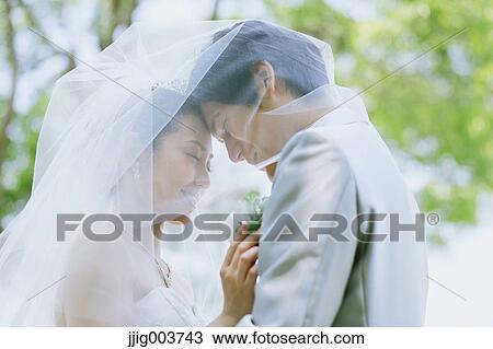 Stock Image - Japanese bride and groom in a city park. Fotosearch