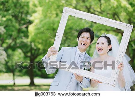 Stock Image - Japanese bride and groom in a city park. Fotosearch