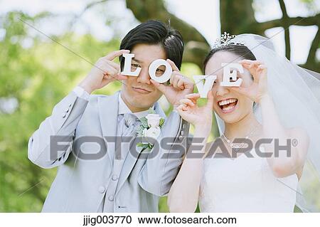 Stock Image - Japanese bride and groom in a city park. Fotosearch