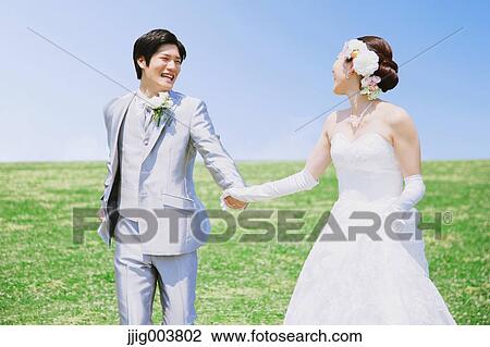 Stock Image - Japanese bride and groom in a city park. Fotosearch