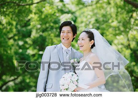 Stock Photo - Japanese bride and groom in a city park. Fotosearch