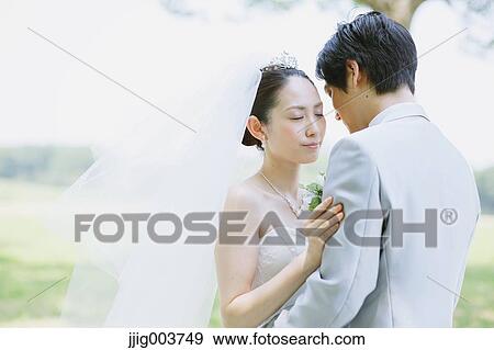 Stock Photo - Japanese bride and groom in a city park. Fotosearch
