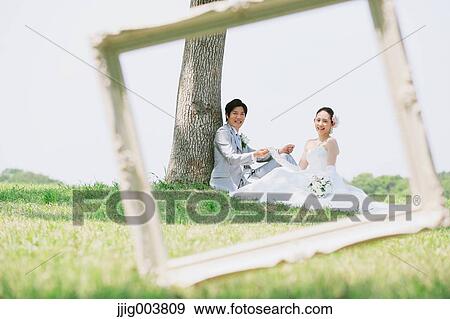 Stock Photo - Japanese bride and groom in a city park. Fotosearch