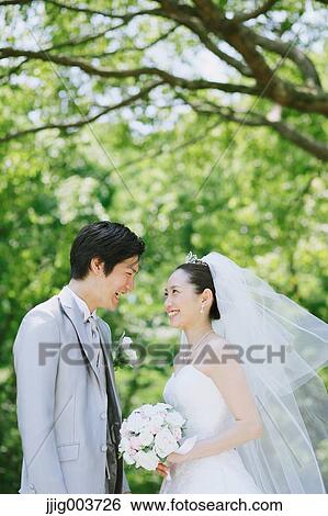 Stock Photograph - Japanese bride and groom in a city park. Fotosearch