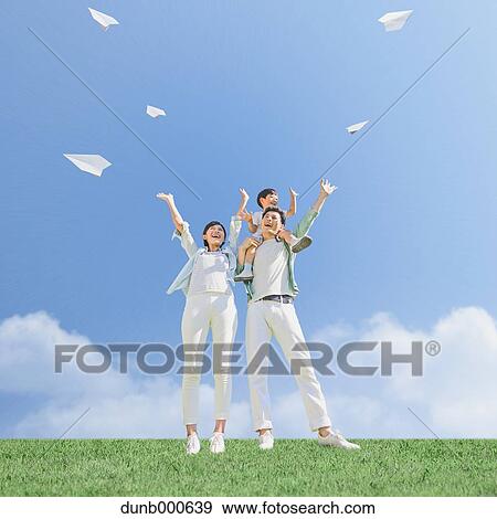 Stock Photo - Japanese family flying paper planes in a city park. Fotosearch