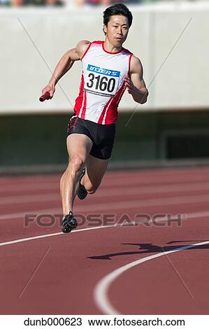 Stock Image - Japanese male sprinter running on track. Fotosearch