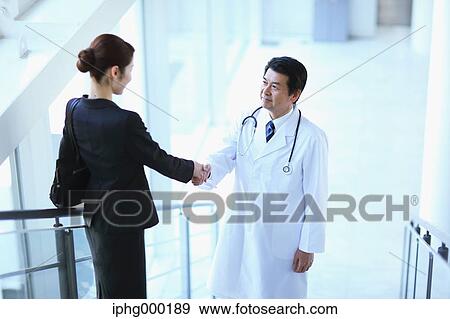 Stock Photo - Japanese senior doctor with businesswoman at the hospital. Fotosearch