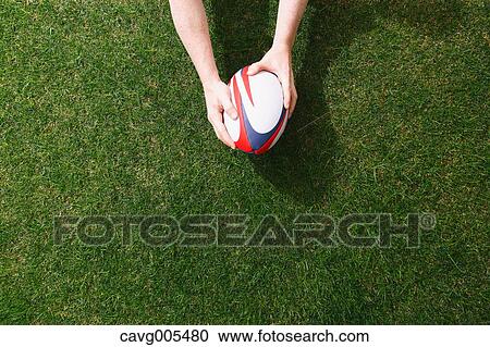 Man holding rugby ball on grass View Large Photo Image Stock Image - Man holding rugby ball on grass. Fotosearch