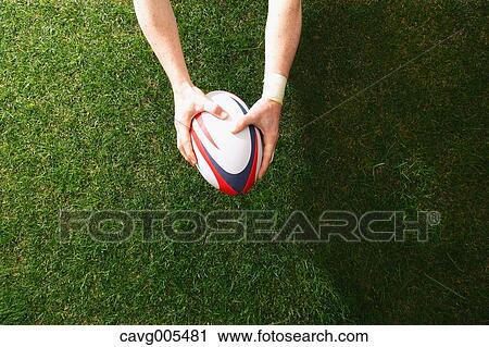 Man holding rugby ball on grass View Large Photo Image Stock Image - Man holding rugby ball on grass. Fotosearch