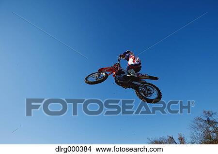 Motocross biker jumping over dirt track View Large Photo Image Picture - Motocross biker jumping over dirt track. Fotosearch
