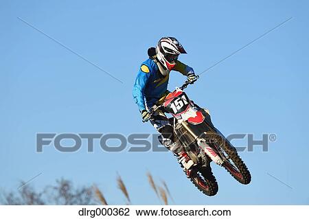 Motocross biker jumping over dirt track View Large Photo Image Stock Image - Motocross biker jumping over dirt track. Fotosearch