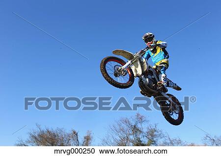 Motocross biker jumping over dirt track View Large Photo Image Stock Image - Motocross biker jumping over dirt track. Fotosearch