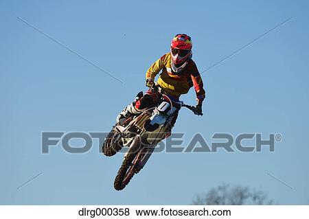Stock Photo - Motocross biker jumping over dirt track. Fotosearch