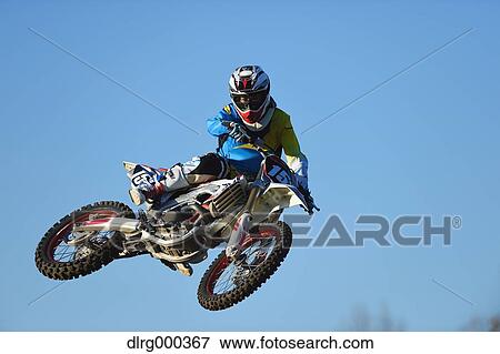 Motocross biker jumping over dirt track View Large Photo Image Stock Photo - Motocross biker jumping over dirt track. Fotosearch