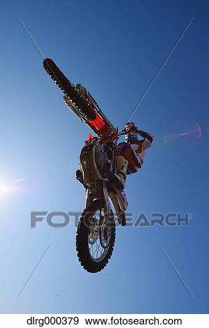 Motocross biker jumping over dirt track View Large Photo Image Stock Photo - Motocross biker jumping over dirt track. Fotosearch
