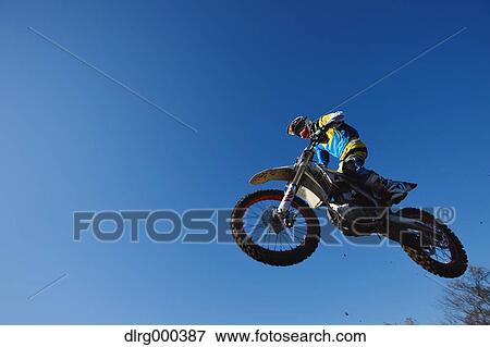 Stock Photo - Motocross biker jumping over dirt track. Fotosearch