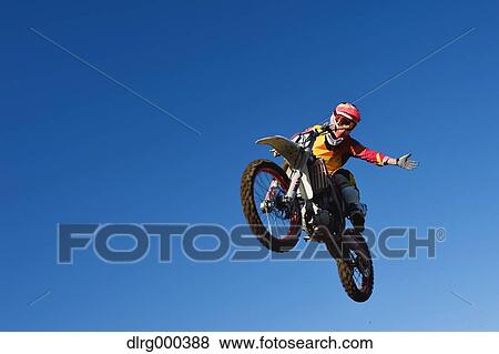 Stock Photo - Motocross biker jumping over dirt track. Fotosearch