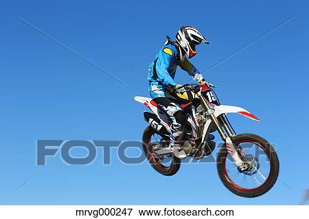 Stock Photo - Motocross biker jumping over dirt track. Fotosearch