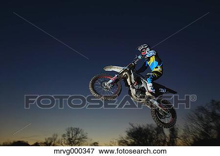 Motocross biker jumping over dirt track View Large Photo Image Stock Photo - Motocross biker jumping over dirt track. Fotosearch