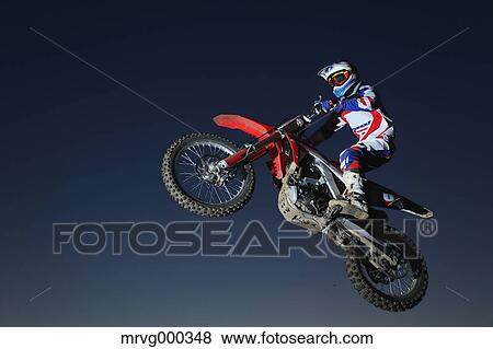 Motocross biker jumping over dirt track View Large Photo Image Stock Photo - Motocross biker jumping over dirt track. Fotosearch