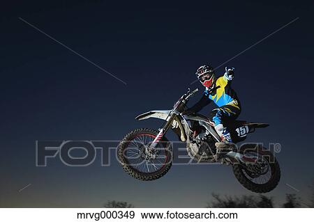 Stock Photo - Motocross biker jumping over dirt track. Fotosearch