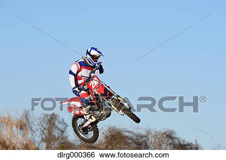 Motocross biker jumping over dirt track View Large Photo Image Stock Photograph - Motocross biker jumping over dirt track. Fotosearch
