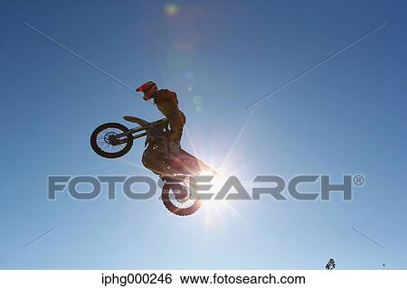 Motocross biker jumping over dirt track View Large Photo Image Stock Photograph - Motocross biker jumping over dirt track. Fotosearch